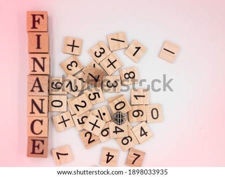 IN selective focus of number cubes put beside blurred FINANCE word writter on wood block,blurry light around