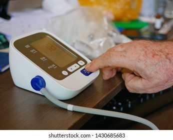 Selective Focus Of An Old Man's Hand Placed Next To The Monitor Checking His Blood Pressure At Home By Himself