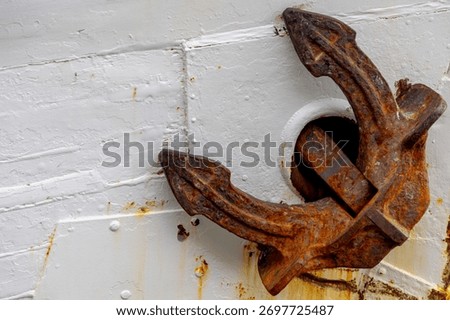 Selective focus of old rusty of anchor, A heavy object attached to a cable or chain and used to moor a ship to the sea bottom, A metal shank with a pair of curved with white metal seal of the ship.