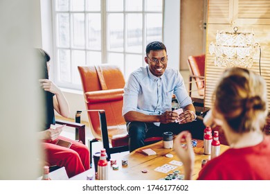 Selective Focus On African American Male Hipster In Optical Eyewear For Vision Protection Communicating With Diverse Friends Discussing Blackjack Rules During Poker Meeting In Loft Apartment