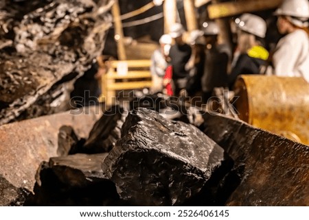 Selective focus on anthracite coal on a conveyer belt with defocused group in the Lackawanna Coal Mine Tour at McDade Park.