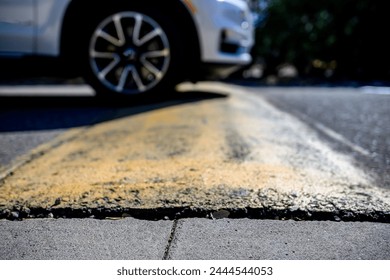 Selective focus on area in front of a speed bump with a car driving over.