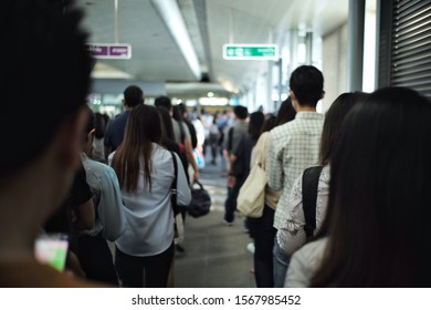 Selective focus on back portrait of people stand in the long line waiting for the train in the station during rush hours. Lifestyle in the big city