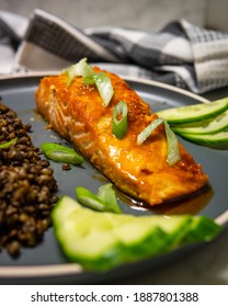 Selective Focus On A Baked Honey-soy Glazed Salmon Fillet Served With Black Beluga Lentils With Cucumber And Green Onions. Healthy Fresh Salmon Steak For Lunch Or Dinner. Side View