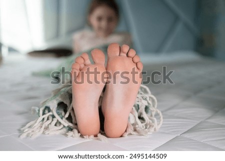selective focus on the bare feet of a child lying on the bed under a blanket. Good morning. Good night. Cozy childhood, sleep with pleasure, childish tenderness, healthy feet