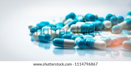 Selective focus on blue and white capsules pill on white background. Antibiotics drug resistance. Antimicrobial capsule pills. Pharmaceutical industry. Pharmacy drugstore products. Pharmaceutics.
