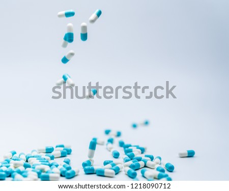 Selective focus on blue-white capsule pill fall down to white table. Antibiotic drug use with reasonable. Antibiotic drug resistance. Pharmaceutical industry. Antimicrobial drug market. 