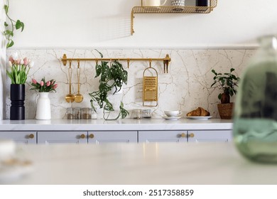 Selective focus on bright kitchen counter with home decor plants, flowers and utensils. Marble countertop with accents in a modern design and copy space