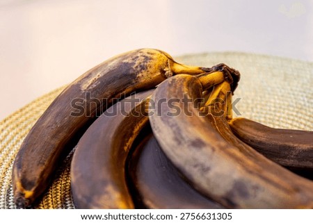 Selective focus on a bunch of almost overripe bananas with blackened tips on a pale green napkin on a table. This is the result of natural processes. High quality photo