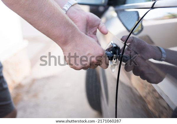 Selective focus on car key remote\
and tools in man\'s hand open the car door. life\
concept.Close-up