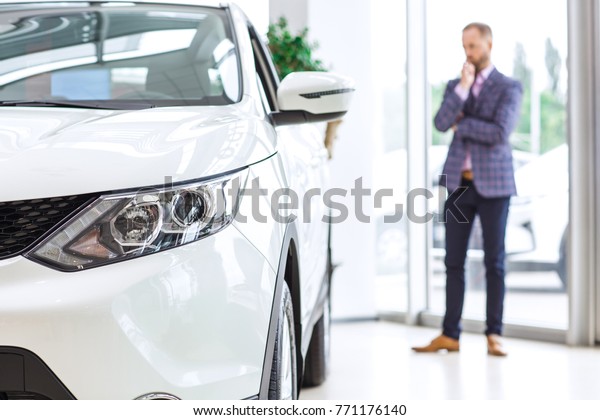 Selective focus on a car lights man\
examining automobiles thoughtfully on the background copyspace\
buying choosing consumer customer buyer sales vehicle travelling\
retail rental\
transportation.