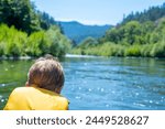Selective focus on a child rafting down the wild and scenic Rogue River while wearing a life jacket