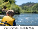 Selective focus on a child rafting down the wild and scenic Rogue River while wearing a life jacket