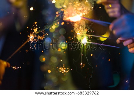 In selective focus on close-up sparklers fireworks in hands.Happy friends having fun with sparkler.Happiness Diverse Ethnic Friendship  Celebration Party Leisure nightlife people concept.Copy space.