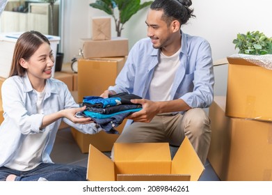 Selective Focus On Clothes Of Attractive Young Asian Couple Prepare Old Used Clothes And Put Into The Box For Donate Or Sharing Another People. Product Recycle Or Volunteer Sharing Donation Concept.