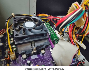 selective focus on the components inside a computer desktop. there are wires of various colors, white sockets, purple and green circuit boards, black cooling fans and various other types components  - Powered by Shutterstock - Get 15% off with code: PIKWIZARD15