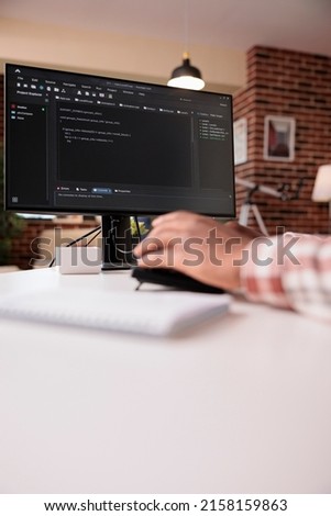 Selective focus on computer screen of african american programmer working remote from home developing software on pc. System developer writing code on personal computer typing algorithm on keyboard.