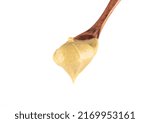 Selective focus on Dijon mustard on top of wooden spoon on white background. The wooden spoon is blurry. Copy space.