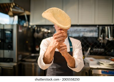 selective focus on the dough that the chef throws up the air. Process of making a pizza base - Shutterstock ID 2005558250