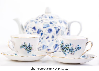 Selective Focus On Elegant Fine China Tea Cups In Blue Floral Pattern With Tea Pot  Out Of Focus In Background.