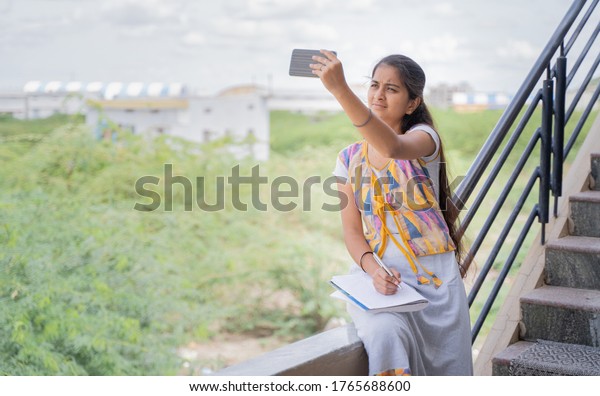 selective focus on face, College girl outside\
home watching online class due to slow internet connection -\
concept of network issue at remote places and problem of virtual\
class or distance\
learning