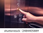 Selective focus on forefinger pressing on button in the passenger lift. Close up of elevator control panel in building. Passenger elevator cabin presses floor selection button. Knob with Bell alphabet