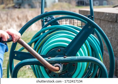 Selective Focus On Front Bar On A Wound Garden Hose Storage Cart With Small Child Spinning Lever