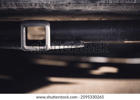 Selective focus on the front end of an empty square hitch receiver on the back end of a vehicle. 