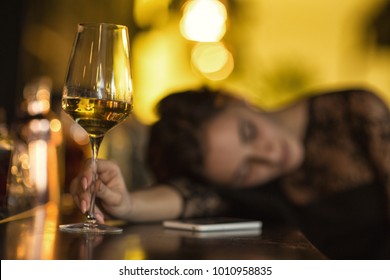 Selective focus on a glass of wine on the bar counter drunk woman sleeping after drinking too much on the background copyspace alcohol alcoholic passed out party depression depressed wasted addiction