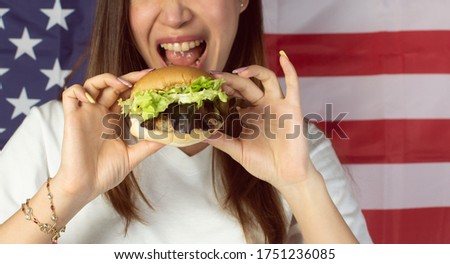 Selective focus on hamburger with background of woman and american flag for celebrating Independence day on 4th of July