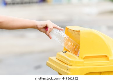 Selective focus on hand dropping empty plastic bottle to the yellow garbage bin. - Shutterstock ID 449361952