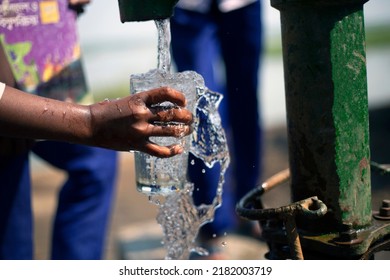 Selective focus on the hand holding glass and splash of clean water from the tube well.Children having fresh water from the tube well in a rural village to hydrate the body in the hot summer. - Powered by Shutterstock