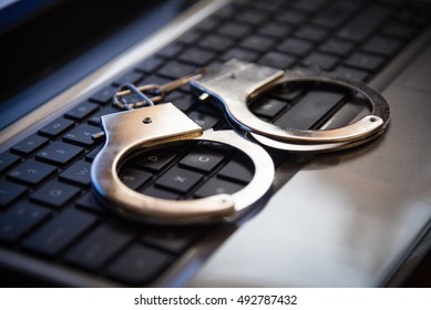 Selective focus on handcuffs on a keyboard cyber crime, hacking, bullying Against law concept in dark low key tone - Shutterstock ID 492787432