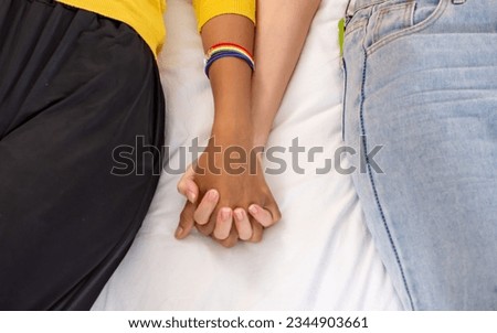 Selective focus on hands holding together of LGBT female lesbian, laying down on bed in bedroom at home. Showing no limited Love Concept