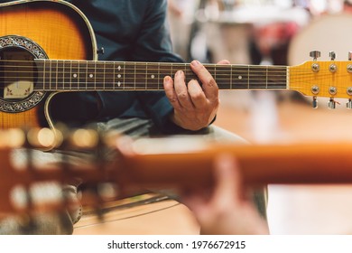 Selective Focus On The Hands Of An Older Man Playing The Guitar In Duet With A Woman.