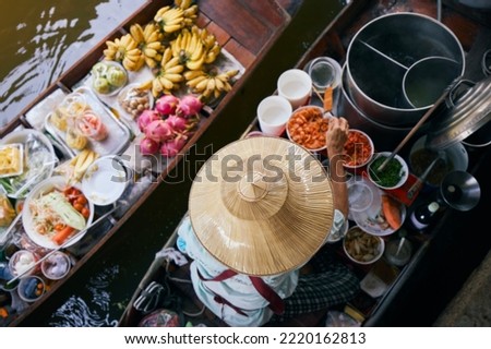 Selective focus on hat of vendor on boat on traditional floating market Damnoen Saduak near Bangkok, Thailand.	