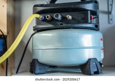 Selective Focus On A Hose Connected To A Pancake Air Compressor Sitting On A Shelf