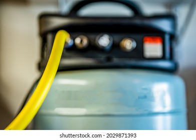 Selective Focus On A Hose Connected To A Pancake Air Compressor Sitting On A Shelf