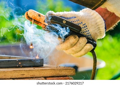Selective focus on a hot electrode in the hand of a welder welding metal. Welding and cutting of metal with an electric welding machine.