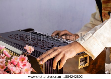 selective focus on human hand playing harmonium - indian classical instruments