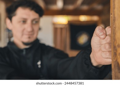 Selective focus on a man's fist training martial arts with a wooden dummy in the practice room. - Powered by Shutterstock