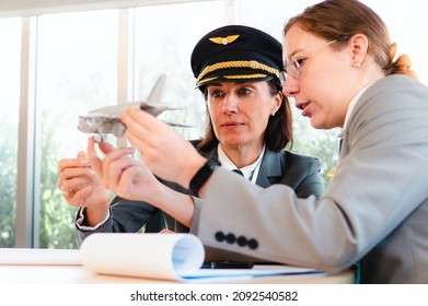 Selective focus on mature commercial female pilot intentional training young flight crew. Beautiful middle aged woman airplane captain flight instructor has meeting discussion education with aircrew. - Powered by Shutterstock