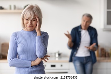 Selective focus on mature lady touching her head and crying, having quarrel with her husband, kitchen interior. Crisis in marriage for seniors, divorce at older ages concept - Powered by Shutterstock