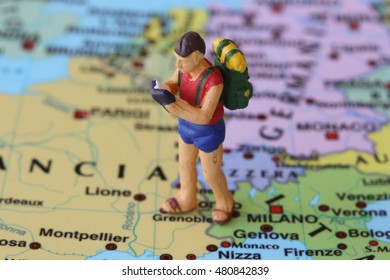 Selective Focus. On Miniature Of Young Turist Boy With Hat Posing On European Map Streets. Tourism And Study Travel Concept.