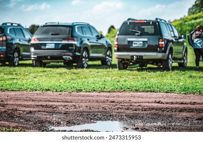 Selective focus on mud and torn up grass in the foreground of a dirt parking lot