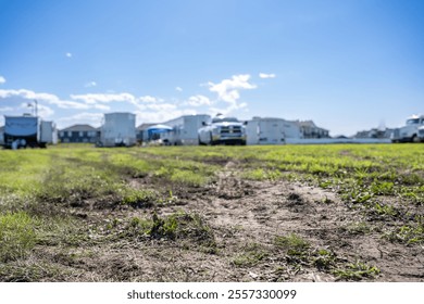 Selective focus on mud and torn up grass in the foreground of a dirt parking lot