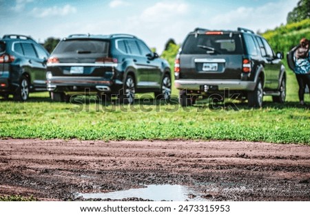 Selective focus on mud and torn up grass in the foreground of a dirt parking lot