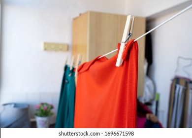 Selective focus on the needle holding a piece of clothing hanging from a string inside a room in a house