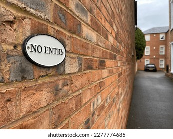 Selective focus on no entry sign on brisk wall, residential building on background