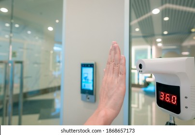 Selective focus on non-contact temperature assessment device. People check body temperature by infrared digital thermometer for screening fever of coronavirus. Palm scan at infrared thermometer.  - Powered by Shutterstock